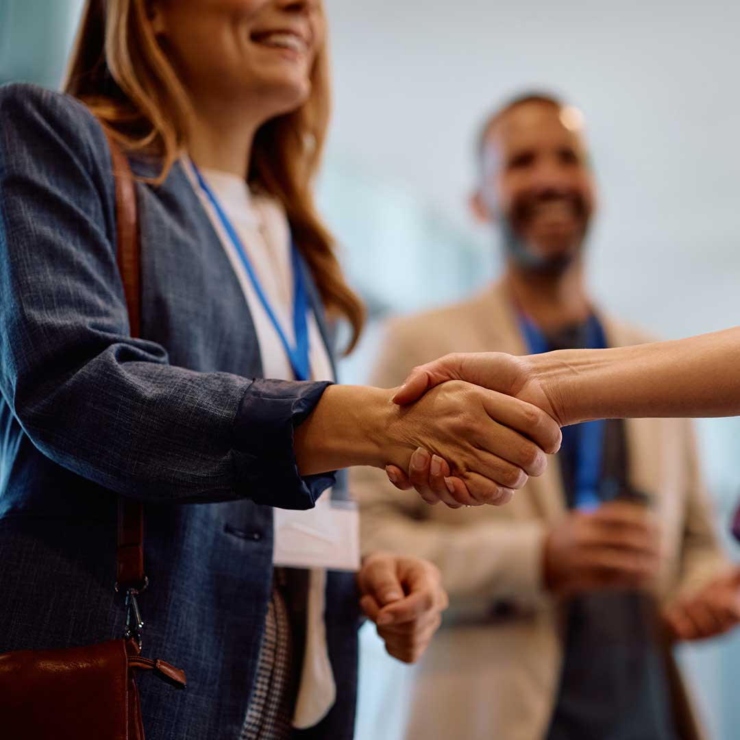 Eine schick gekleidete Frau schüttelt die Hand einer anderen Person