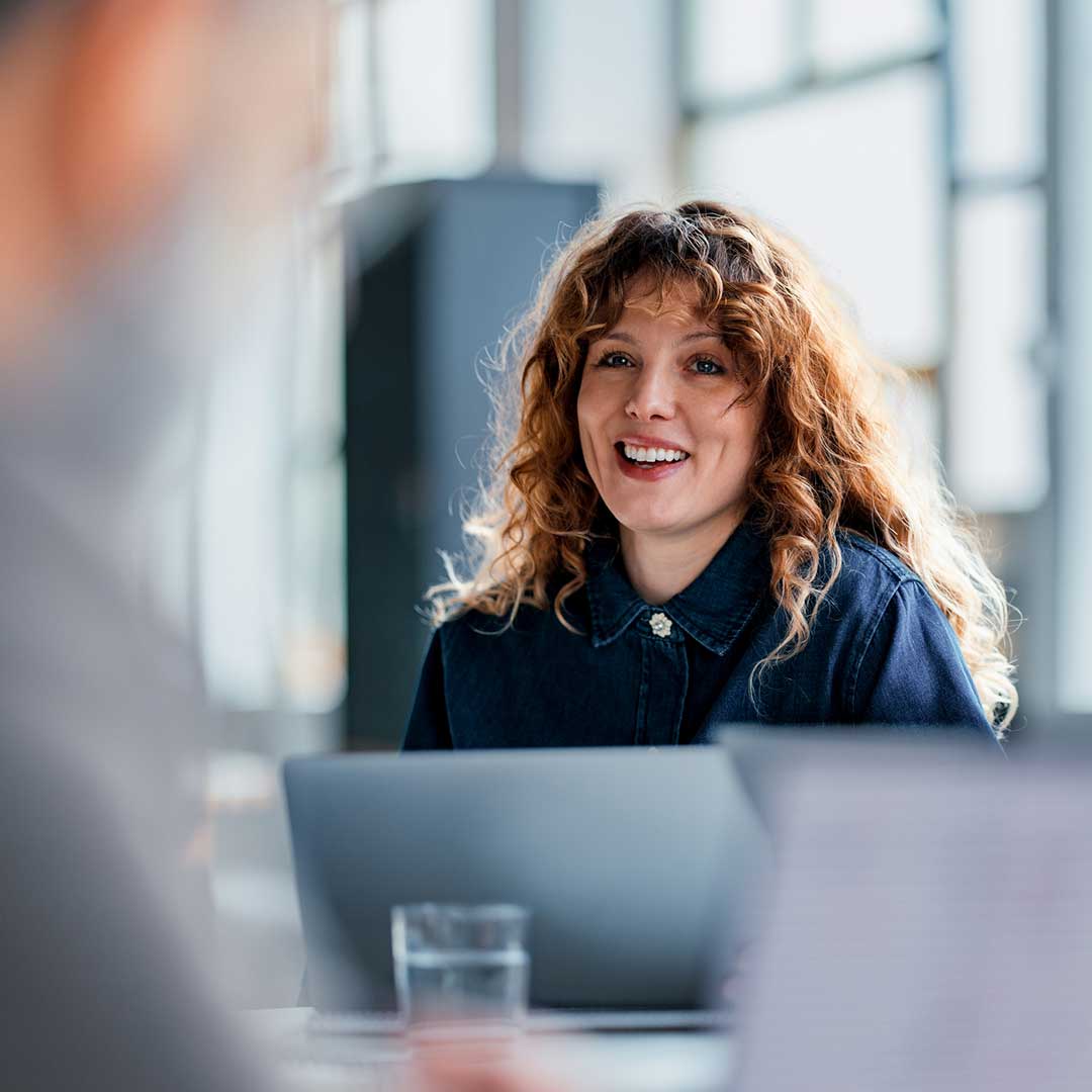 Junge Mitarbeiterin sitzt vor einem Laptop.