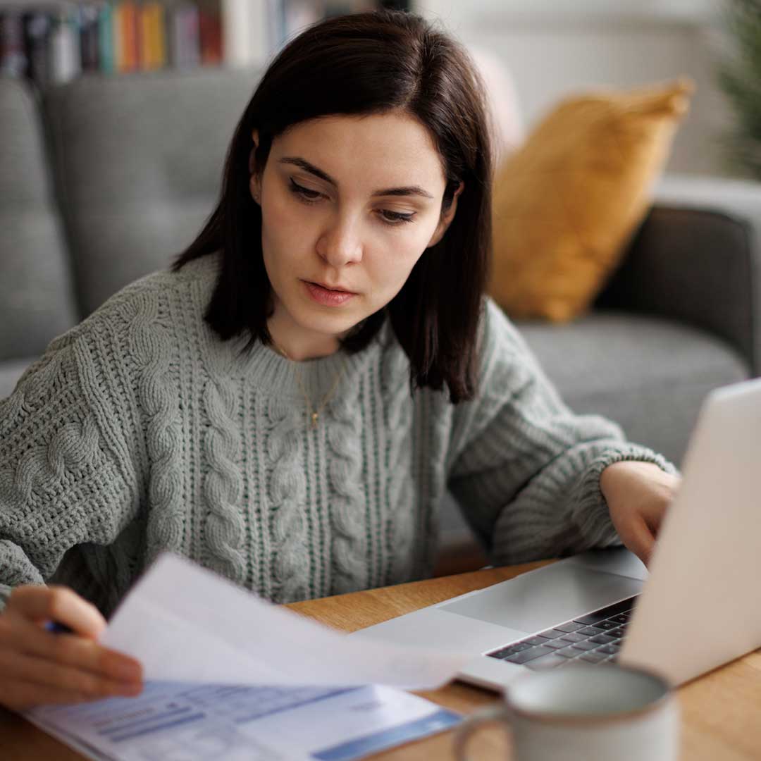 Junge Frau, die zuhause Rechnungen und Ausgaben analysiert.